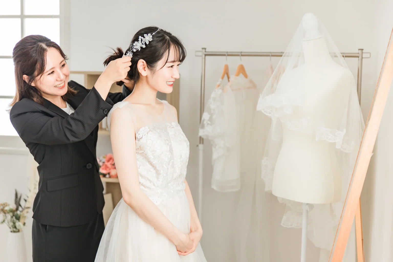 スタッフが花嫁のヘアアクセサリーを整えながら衣装をフィッティングしている様子